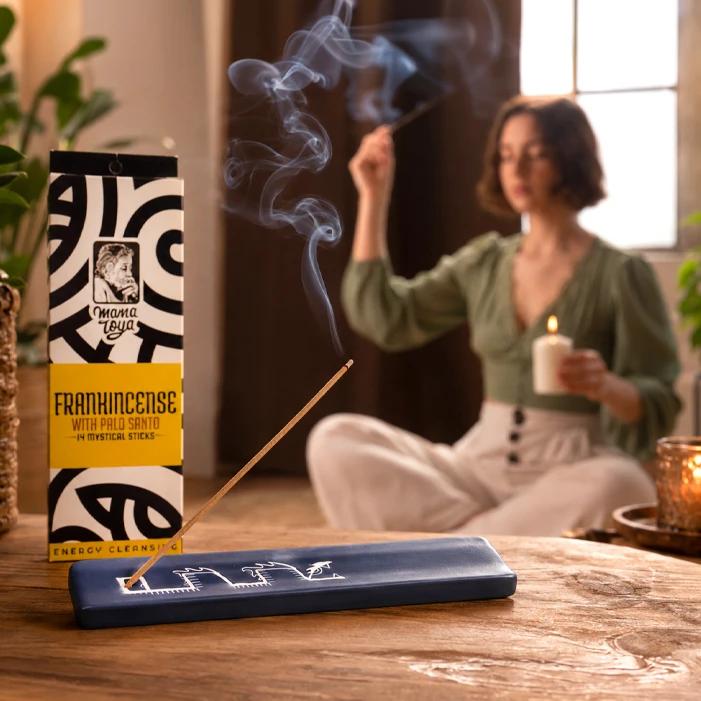 Frankincense with Palo Santo incense stick burning on ceramic holder during a calm cleansing ritual